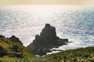 Scenic Rocky Coastline with Sunlit Ocean at Land's End in Cornwall, UK photo