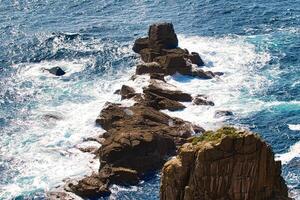 Aerial View of Rocky Coastline with Crashing Waves at Land's End in Cornwall, UK photo