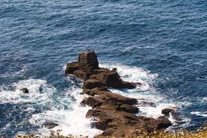 Rocky Outcrop in Deep Blue Ocean at Land's End in Cornwall, UK photo