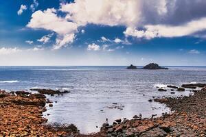 Scenic Coastal View with Rocky Shores and Distant Island at Cape Cornwall photo