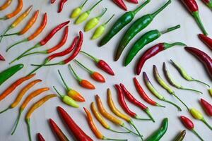 different types of hot pepper in different colors from green to purple. High quality photo hot pepper is laid in neat rows on a light background. autumn backgrounds with ripe vegetables