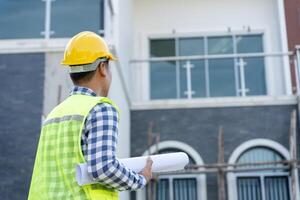 inspector or engineer is inspecting construction and quality assurance new house using a blue print. Engineer or architects or contactor work to build the house before handing it over to the homeowner photo
