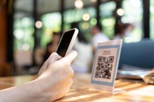 Woman use smartphone to scan QR code to pay in cafe restaurant with a digital payment without cash. Choose menu and order accumulate discount. E wallet, technology, pay online, credit card, bank app. photo
