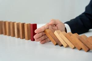 insurance with hands protect domino. Businessman hands stop dominoes falling in business crisis. business risk control and planning and strategies to run prevent insurance businesses. photo