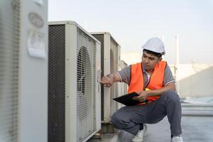 Asian maintenance engineer works on the roof of factory. contractor inspect compressor system and plans installation of air condition systems in construction. Checklist, inspector, control photo
