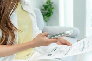 Modern woman use phone to scan barcode or QR codes to pay credit card bill after receive document invoice. payment, receive, paying electricity, digital payments without money, technology, scanning photo