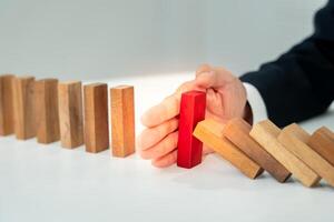 insurance with hands protect domino. Businessman hands stop dominoes falling in business crisis. business risk control and planning and strategies to run prevent insurance businesses. photo