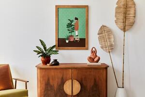 Minimalist composition of living room with brown mock up picture frame, plant, retro armchair, dried tropical leaf, decoration and elegant personal accessories in stylish home decor photo