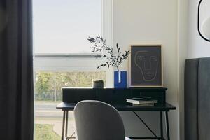 Stylish composition of small modern workspace interior with lamp. Walls with black panels. Panoramic windows with grey curtains. Minimalistic masculine concept. Template. photo