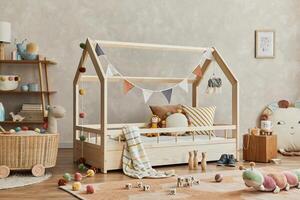 Creative composition of cozy scandinavian child's room interior with wooden bed, plush and wooden toys and textile hanging decorations. Neutral creative wall, carpet on the parquet floor. Template. photo