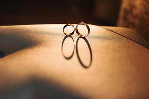 Two wedding rings are on a table, with one ring on top of the other. The rings are gold and have a shiny, polished appearance. Concept of love and commitment photo