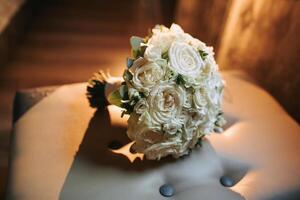 A bouquet of white flowers sits on a chair. The flowers are arranged in a way that they look like they are in a vase. The arrangement is simple and elegant, with the white flowers being the main focus photo