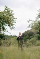 A man in a suit stands in a field of grass. The sky is cloudy and the man is looking up photo