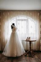 A white dress is displayed in front of a window photo