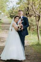 A bride and groom are posing for a picture in front of a tree photo