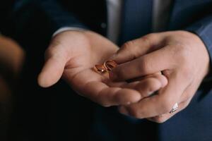 A man is holding two gold wedding rings in his hand photo