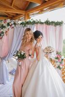 Two women are posing for a picture in front of a pink, purple, and blue backdrop photo