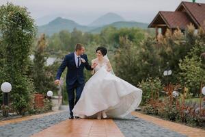A bride and groom are running down a path in the rain photo