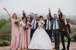 A group of people, including a bride and groom, are posing for a photo on a hill