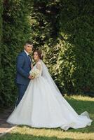 A bride and groom are posing for a picture in front of a bush photo