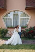 A bride and groom are standing in front of a building with a window photo