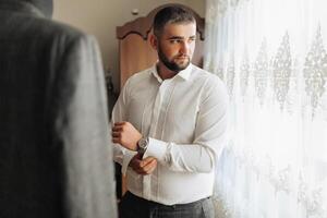 A man in a suit is getting ready to leave and is adjusting his watch photo