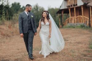 A bride and groom are walking together in a field photo