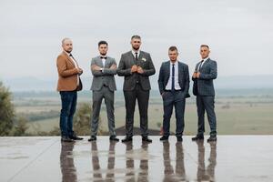 A group of five men are standing on a wet surface, dressed in suits and ties photo