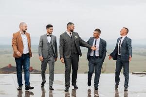 A group of five men dressed in suits and ties are standing on a wet surface photo