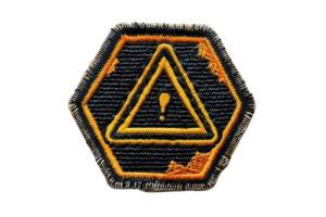 A black and orange embroidered hexagon safety patch with a warning triangle and exclamation mark, symbolizing caution or hazard. png