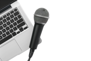 Closeup of a black microphone placed on a silver laptop keyboard, representing work in media, broadcasting, or podcasting. png