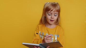 Thoughtful child girl kid making notes, writing down thoughts with pen into notepad notebook diary video
