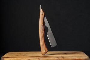 Handcrafted Wooden Folding Knife Displayed on a Rustic Table Against a Dark Background photo