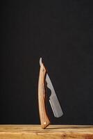 Handcrafted Wooden Folding Knife Displayed on a Rustic Table Against a Dark Background photo