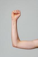 Raised Right Arm With a Clenched Fist Against a Neutral Background photo