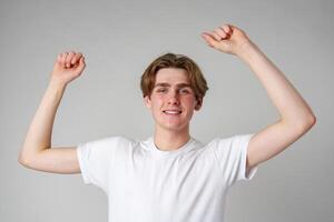 Young Man Celebrating Success With Arms Raised in a Joyful Gesture Indoors photo