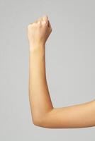 Female hand with clenched fist on gray background photo
