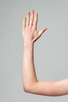 Human Hand Raised Against a Neutral Gray Background in a Studio Setting photo