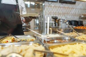 Chef Serving Freshly Cooked Dishes at a Restaurant Buffet During Lunchtime photo