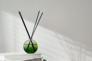 Aromatic Reed Diffuser on White Books With Shadows Playing on the Wall photo