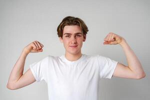 Young Man Flexing Muscles in Front of White Background photo