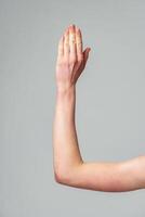 Human Hand Raised Against a Neutral Gray Background in a Studio Setting photo