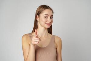 Young Woman Pointing Towards Camera With a Playful Expression in a Studio photo