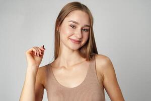 Smiling young woman posing to camera over gray background in studio photo