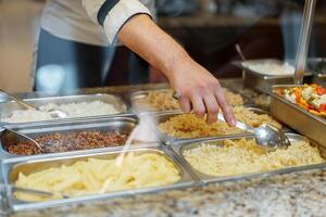 Chef Serving Freshly Cooked Dishes at a Restaurant Buffet During Lunchtime photo
