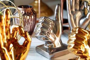 Metallic Thumbs-Up and OK Hand Gesture Sculptures Displayed on a Shelf photo