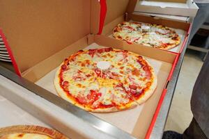 Two Freshly Baked Pizzas in Open Cardboard Boxes Ready for Delivery photo