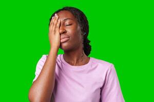 A woman expressing frustration while standing in front of a bright green background photo