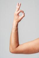 A person hand gesture against a neutral background photo