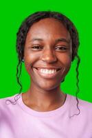 Young woman smiling joyfully in a pink shirt against a vibrant green background in a cheerful atmosphere photo